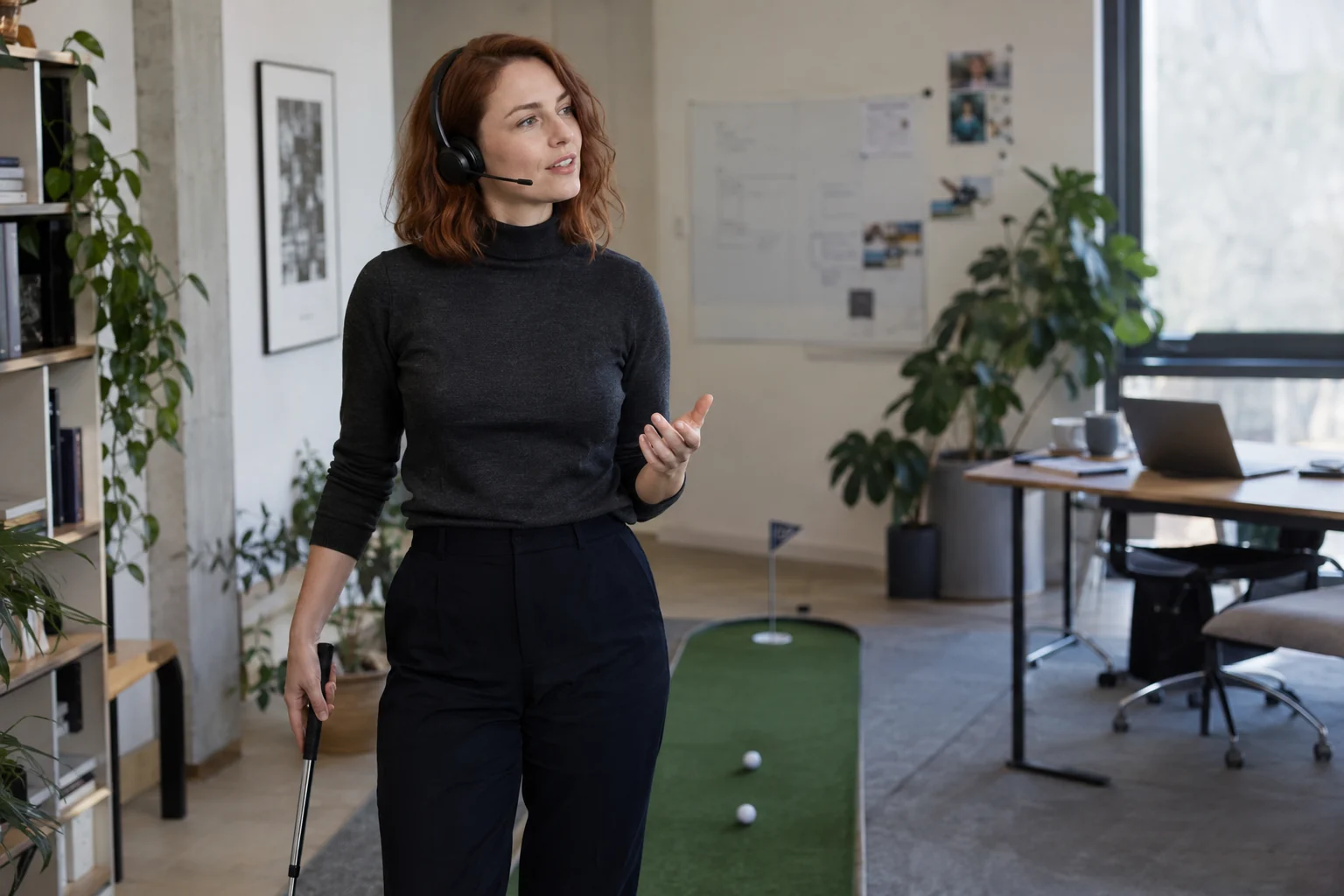 KI-generierte Szene: Eine Person hält beim Büro-Minigolf eine Idee über ihr Headset fest; der Laptop steht im Hintergrund.