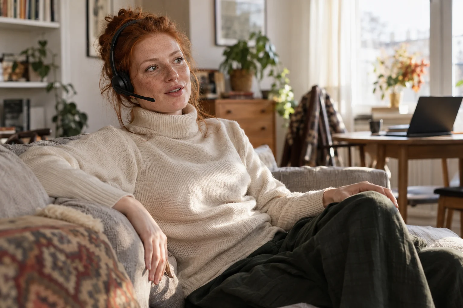 KI-generierte Szene: Eine Person diktiert entspannt auf dem Sofa mit Headset; der offene Laptop steht hinten rechts.